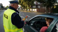 Policjant bada stan trzeźwości kierowcy samochodu osobowego