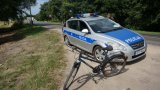 Przy policyjnym radiowozie stoi rower