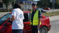 Policjant z wolontariuszką wręczają symboliczne serduszko kierowcy