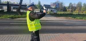 Na zdjęciu policjant ruchu drogowego stojący z ręcznym miernikiem prędkości